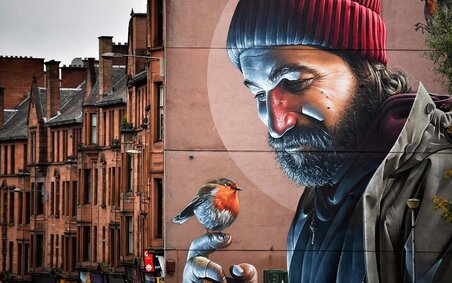 A man is depicted holding a bird, a famous mural on the mural city trail in Glasgow