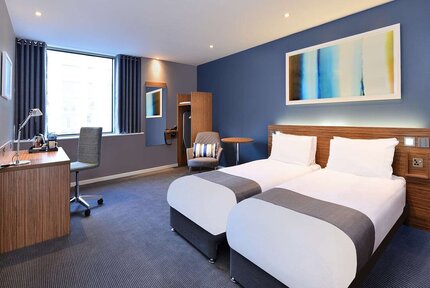 Two twin beds in a lovely decorated blue and white room inside the holiday inn theatreland in Glasgow.